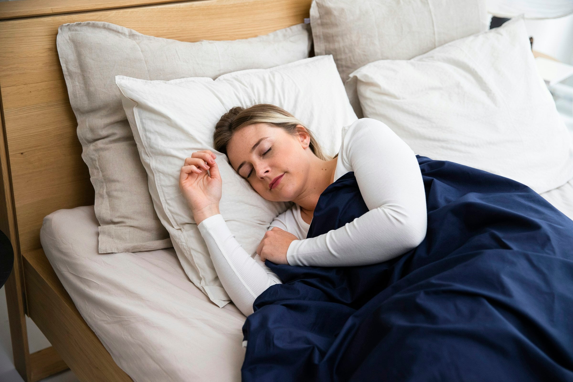 Stack of soft pillows with a navy blue blanket, calm bedroom